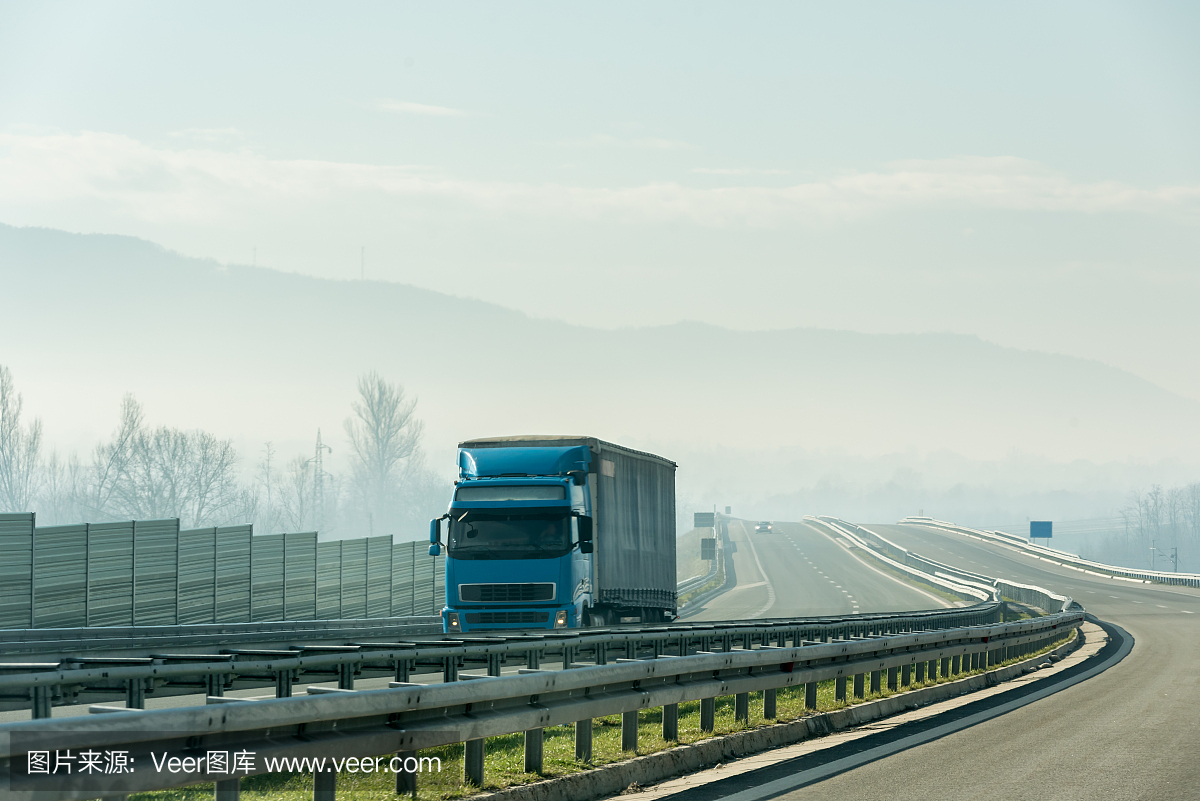 蓝色的卡车在沥青公路上行驶在乡间的风景中